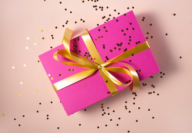 pink gift box with a golf ribbon on it