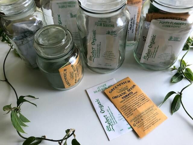 multiple glass jars with packets of seeds in each jar