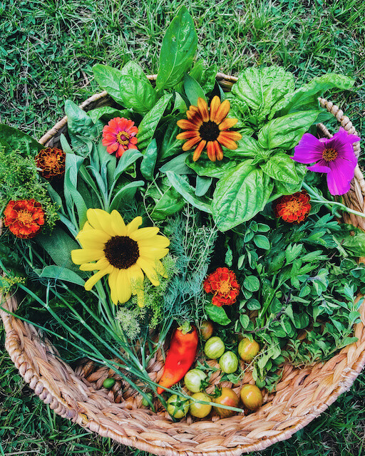 a basket filled with garden vegetables and flowers