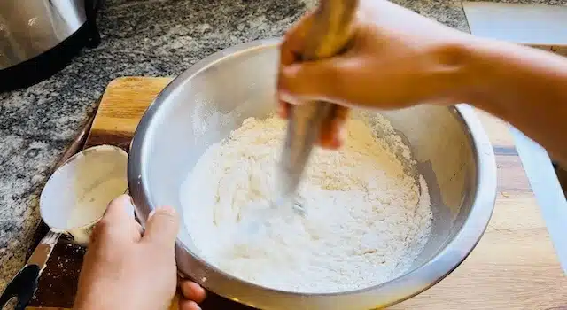 Flour being mixed in a stainless steel bowl